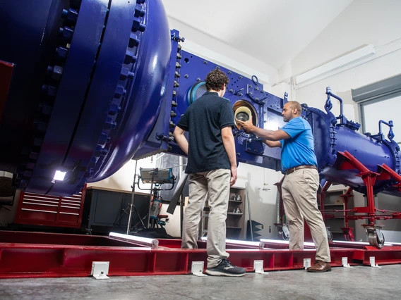 Two men handle parts of a major wind tunnel.