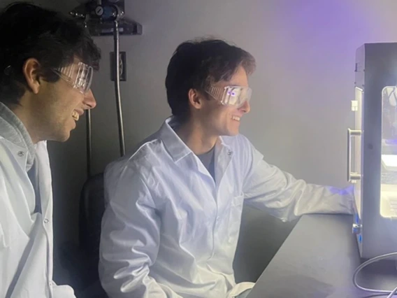 In biomedical engineering assistant professor Shang Song’s lab, undergraduates Ethan Taylor (left) and Lucas Mellinger stand by as a 3D bioprinter creates living cells.