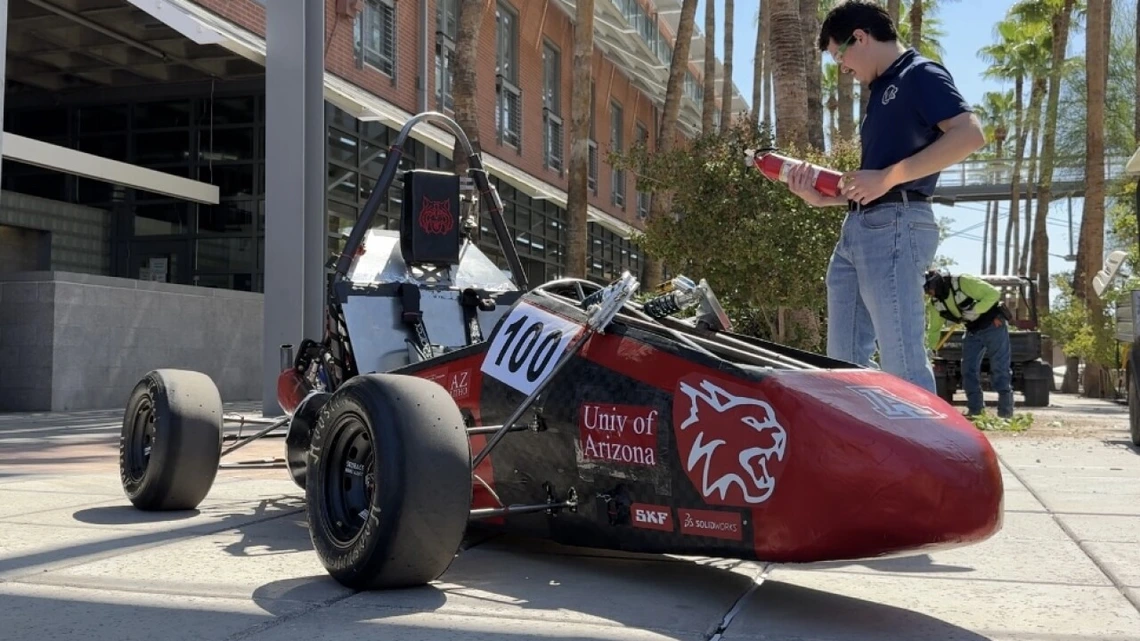 Aerospace and mechanical engineering junior Cooper Graf stands beside the Wildcat Formula Racing club's WF25 vehicle on the University of Arizona campus.