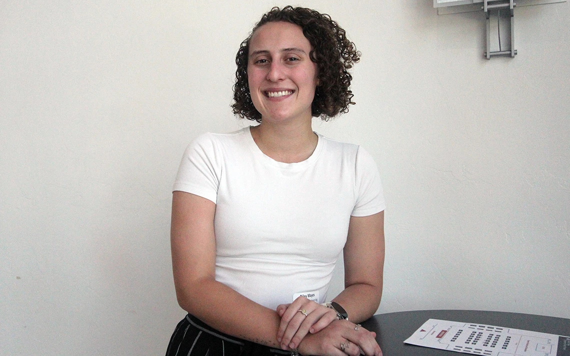 A woman with curly brown hair poses for a photo.
