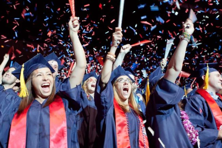 students in graduation regalia, cheering