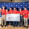 A mixed group of people hold a large check.